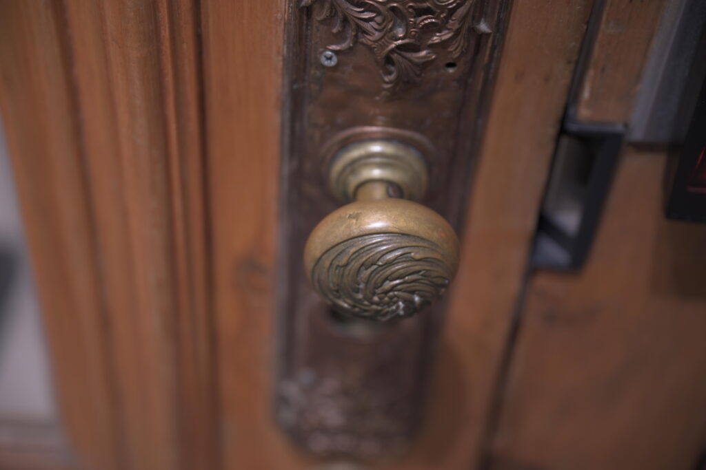 Nineteenth-century brass doorknob and stamped escutcheon plate on a historic door in Quebec City